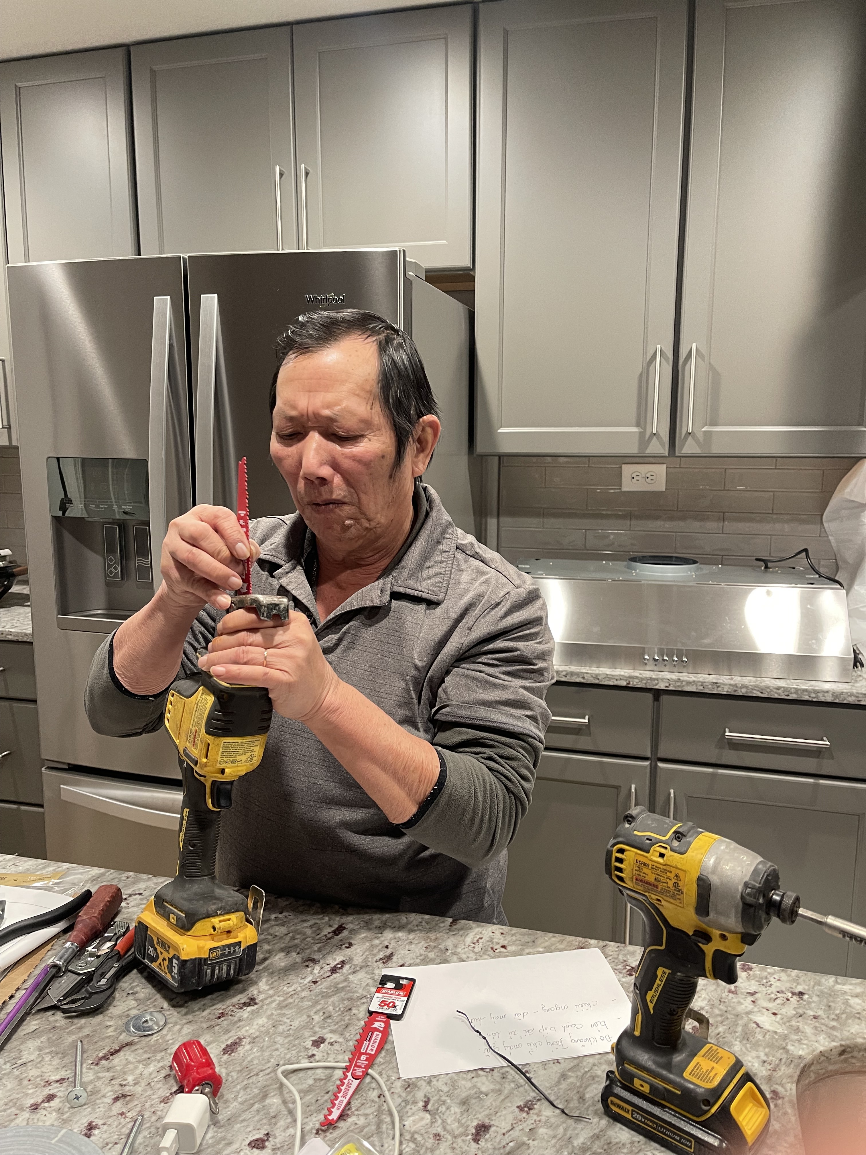 Thuat Le, the founder of Dovesons Construction, fitting a blade into a reciprocating saw with his DeWalt tools on the counter