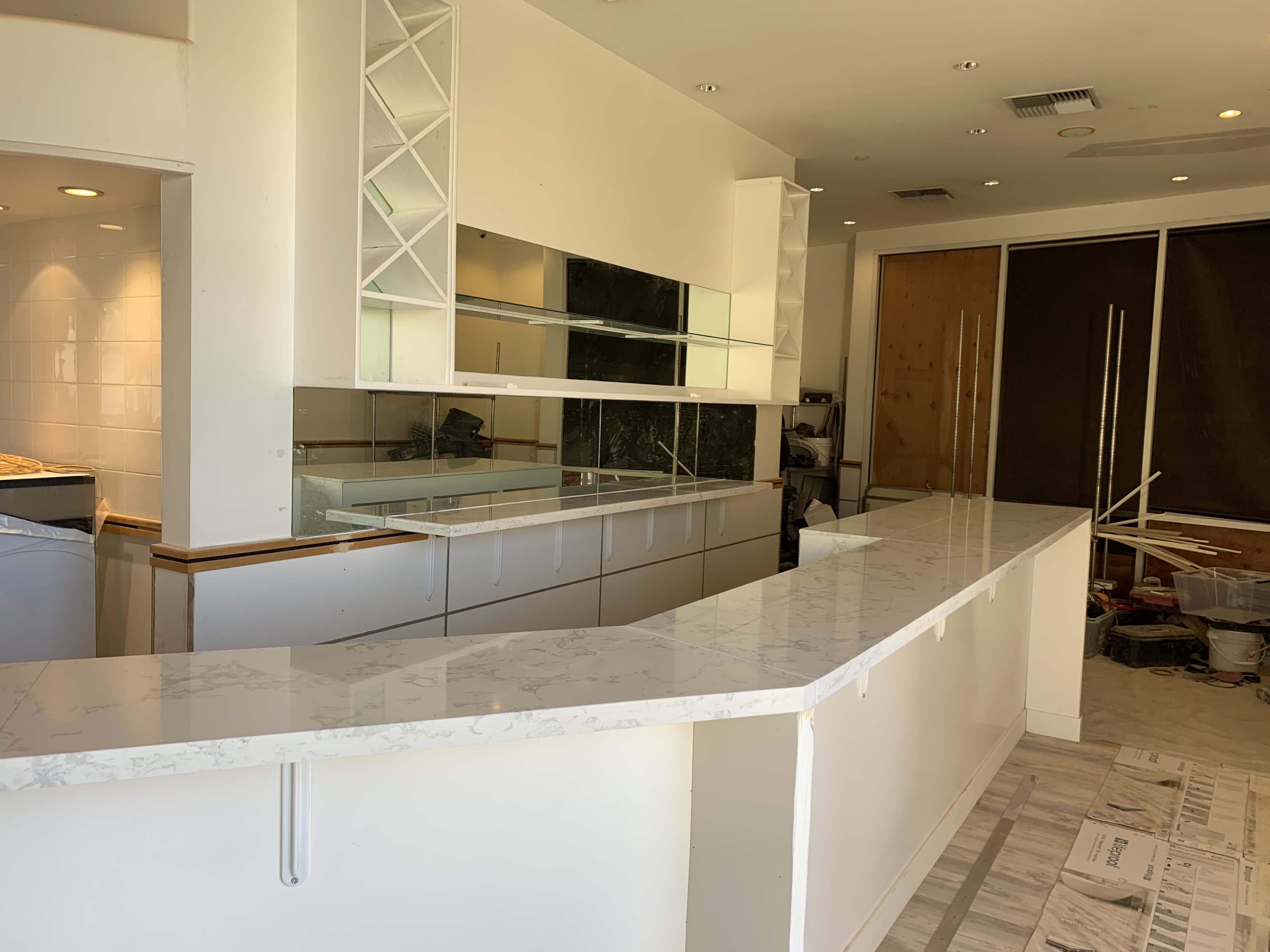 Quartz service counter installed along white cabinets and a mirrored back wall