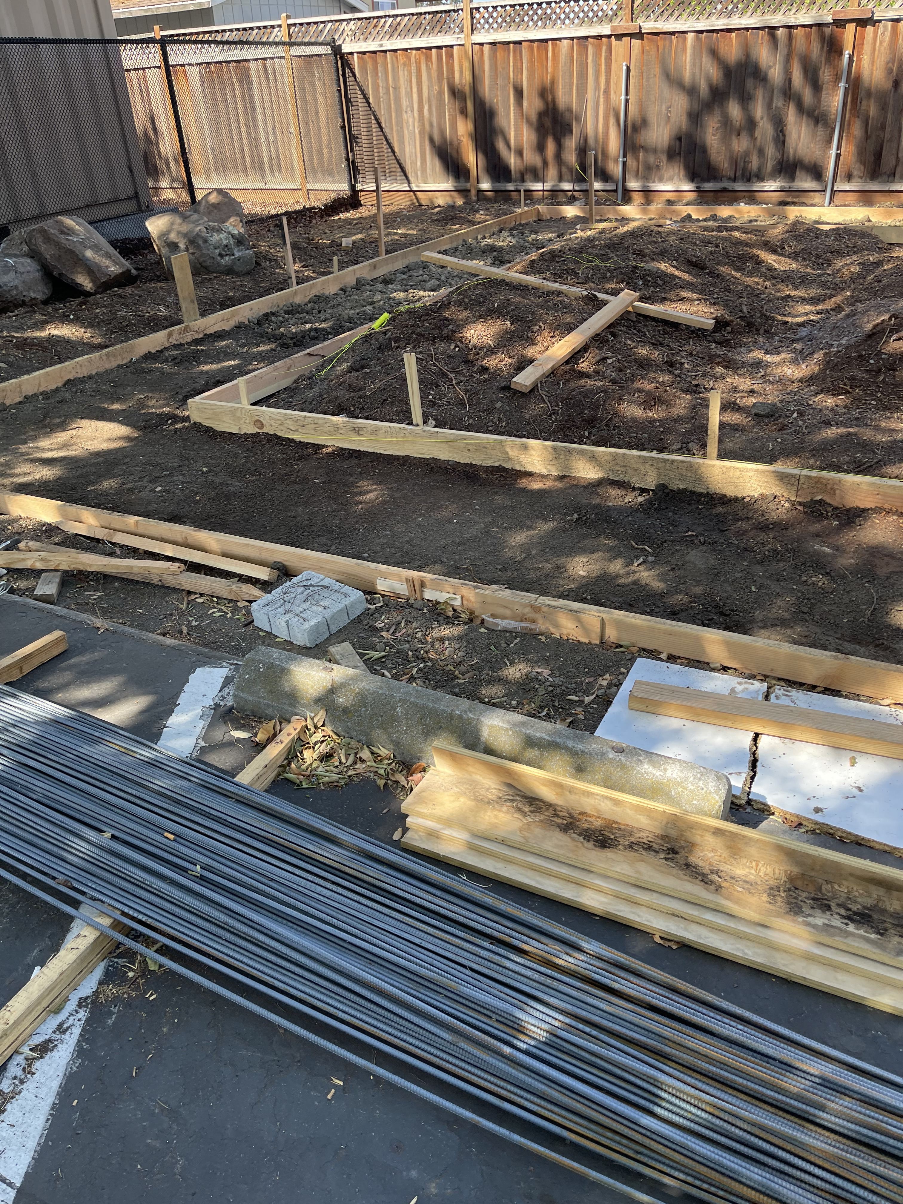 Foundation forms with string lines in graded soil and a bundle of rebar in the foreground