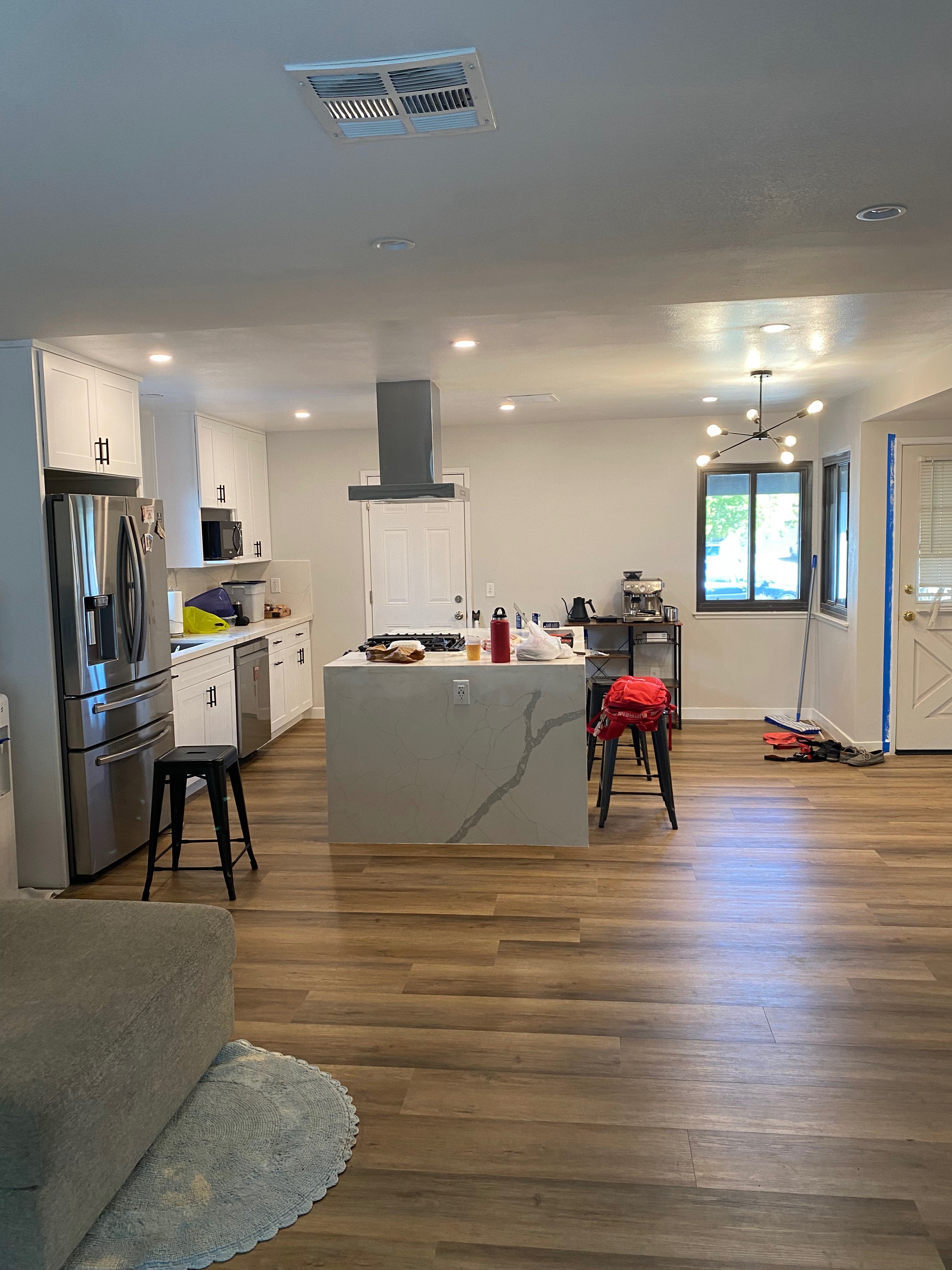 Finished open-plan kitchen with white shaker cabinets, a waterfall quartz island and vinyl plank floors